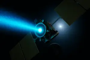 अंतरिक्ष में नीली आयन ऊर्जा उत्सर्जित करता हुआ एक उन्नत आयन थ्रस्टर।